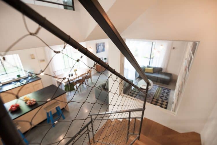 מבט מהמדרגות עם מעקה רשת אקסטנדד מנירוסטה לכיוון קומת הכניסה המטבח והסלון בבית בהרצליה