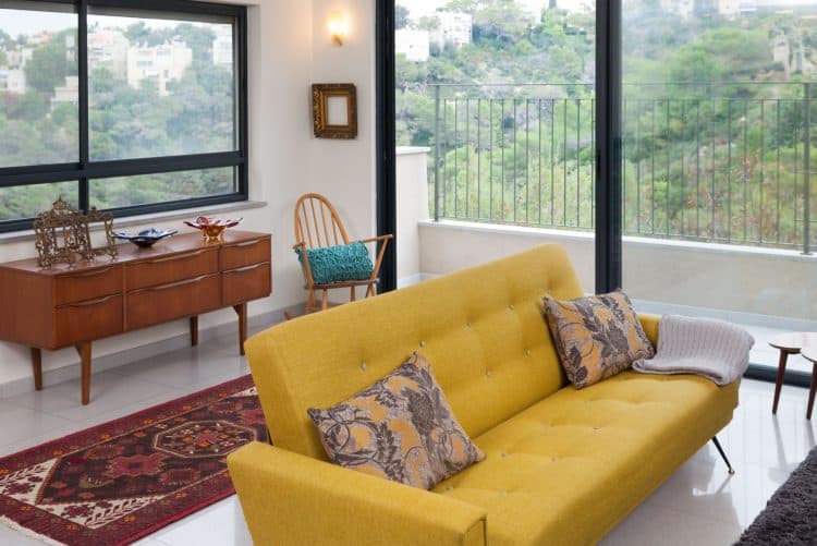 מבט מהסלון לכיוון מרפסת סלון והנוף של הכרמל היפה. ברקע ספת וינטג' מקורית מרופדת בגוון צהוב