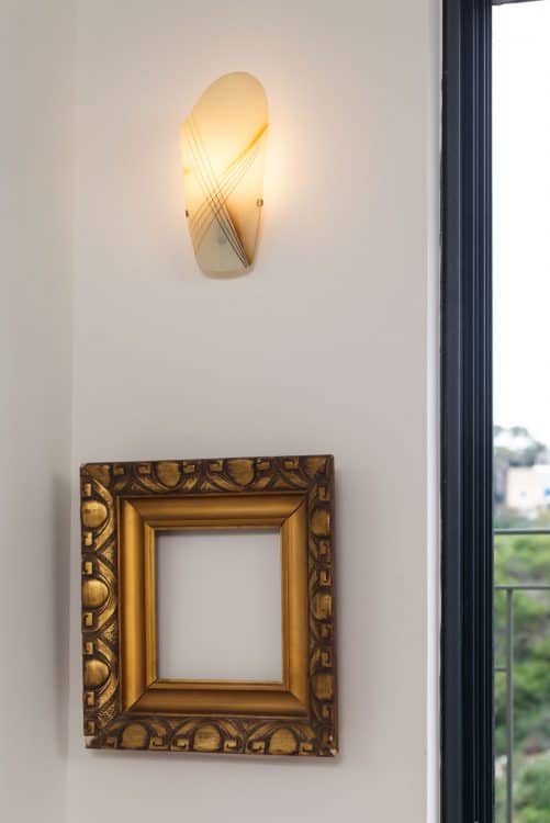 גוף תאורה ומראה על קיר וינטג' מקורי בבית בשכונת כרמליה בחיפה