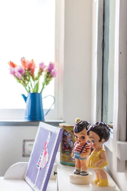 מבט לשידת טואלט בחדר שינה בנות ועליה מונחים פסלי קרמיקה צבעוניים, של ילדים, של האמנית פוגי נעים.