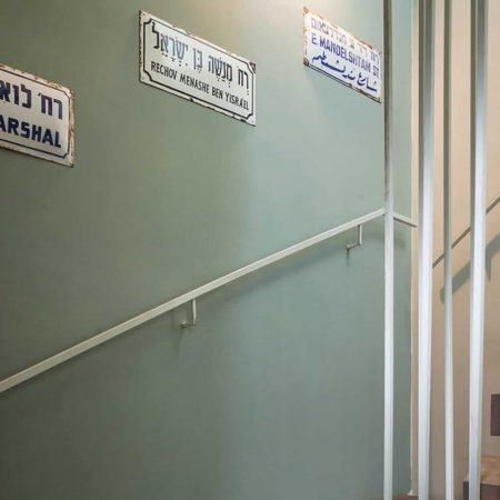 שלטי רחוב ישנים וינטג' על רקע קיר ירוק אפור במהלך מדרגות בדירת גג בתל אביב בעיצוב שרון אלה